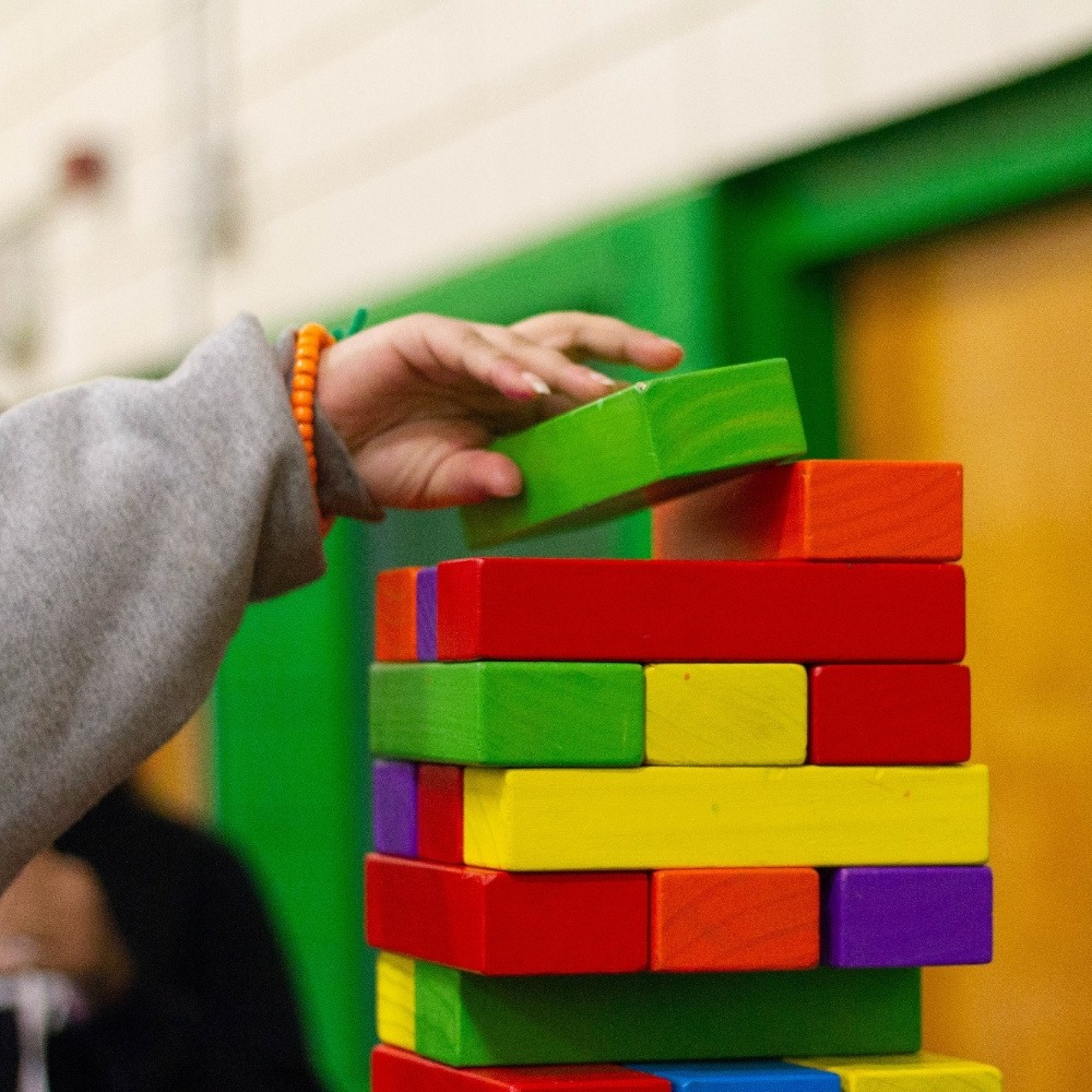 Close-up of person stacking multicoloured building blocks